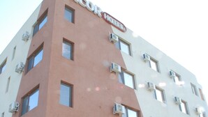 A hotel with a modern design, featuring a prominent 'ANCOR HOTEL' sign at the top. The building has multiple air conditioning units attached to the exterior walls. - Ancor Hotel (Voluntari)