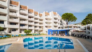 Un hotel con varios pisos, piscina al aire libre y zona de estar con sillones.