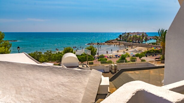 Vista costera con playa, palmeras y cielo despejado.