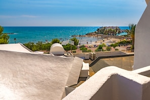 Vista costera con playa, palmeras y cielo despejado.