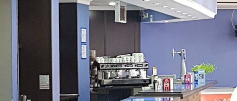 A cafe with a blue counter, brick wall, and white chairs.