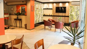 Un moderno vestíbulo de hotel con mostrador de recepción, zona de estar y una planta grande.