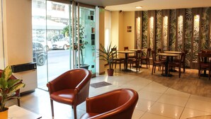 Un vestíbulo de hotel con zona de estar, una planta en maceta y vistas a la calle.