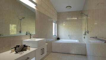A modern bathroom with a large mirror, two sinks, a bathtub, and a shower.