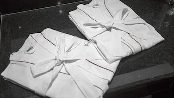 Des serviettes blanches, soigneusement pliées et ornées de nœuds, sont posées sur une surface sombre.
