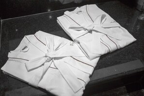 Neatly folded white towels with bows on a dark surface. - Palais Hotel (Sao Vicente)