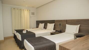 Two single beds with white pillows and bedside tables, a wooden desk, and a lamp.