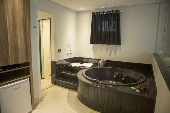 Un baño moderno con una bañera grande, zona de ducha e horno empotrado.