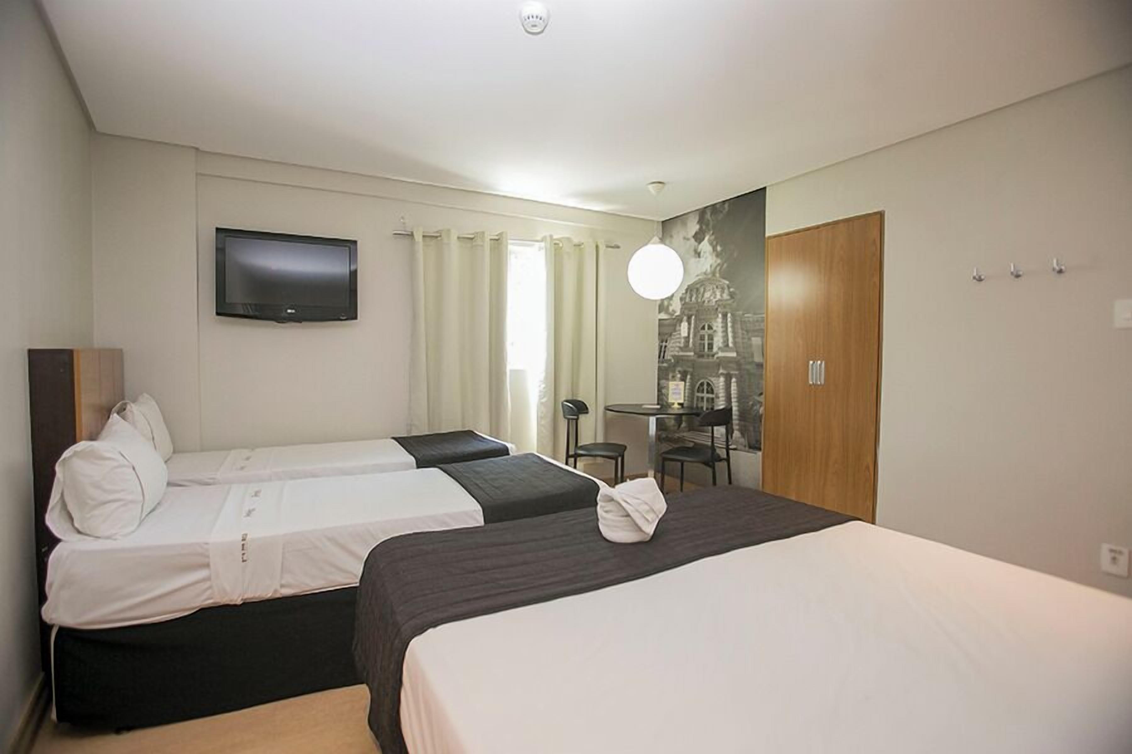 Une chambre d’hôtel avec deux lits, une télévision, un bureau et une armoire.