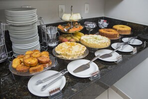 A buffet with various food items and utensils. - Palais Hotel (Sao Vicente)