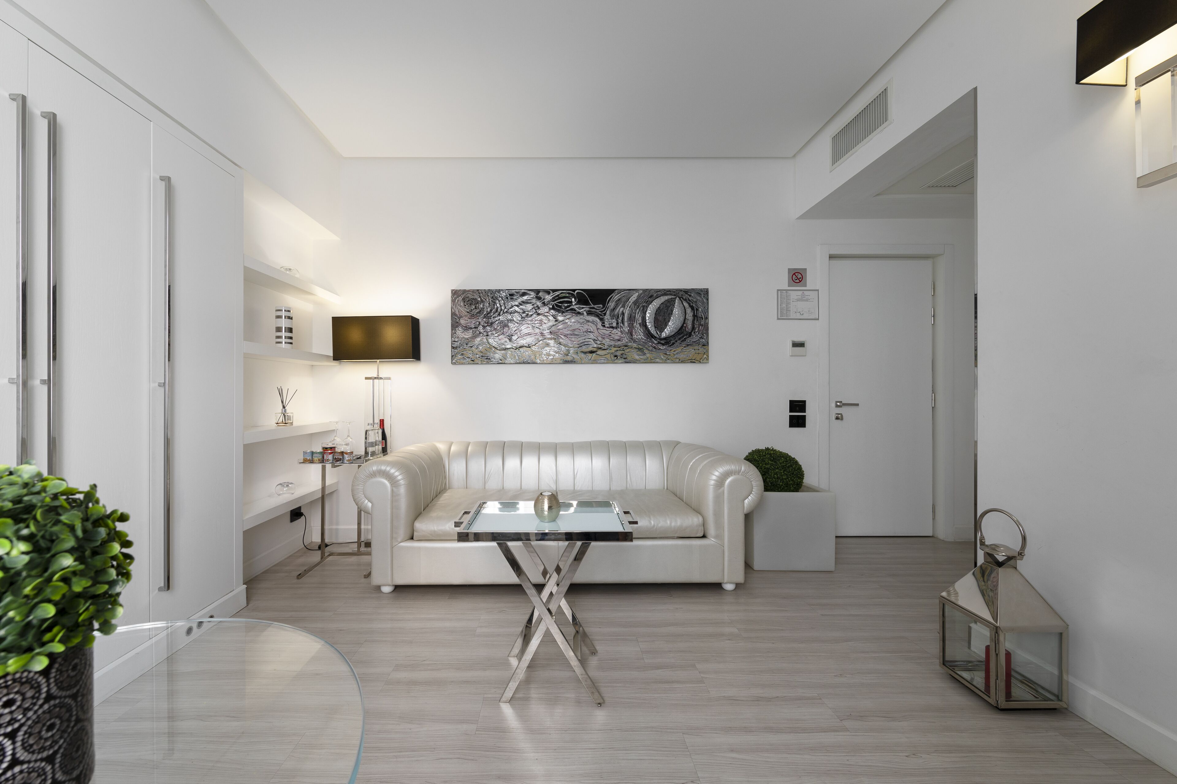 Un salon moderne avec un canapé en cuir blanc, une table basse en verre et une décoration minimaliste.