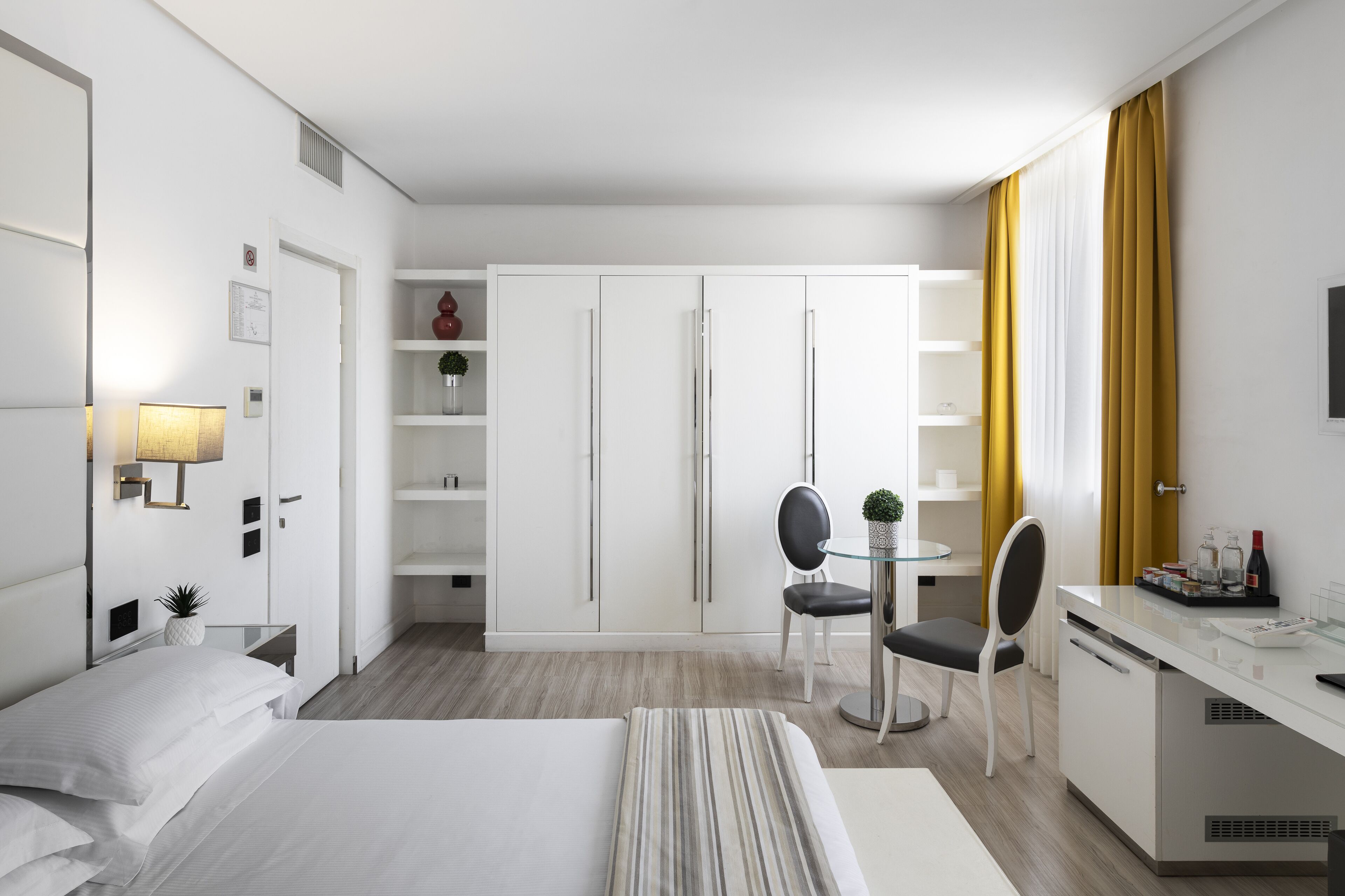 Una camera d'albergo moderna con un letto, una scrivania, una sedia, un tavolino e un armadio.