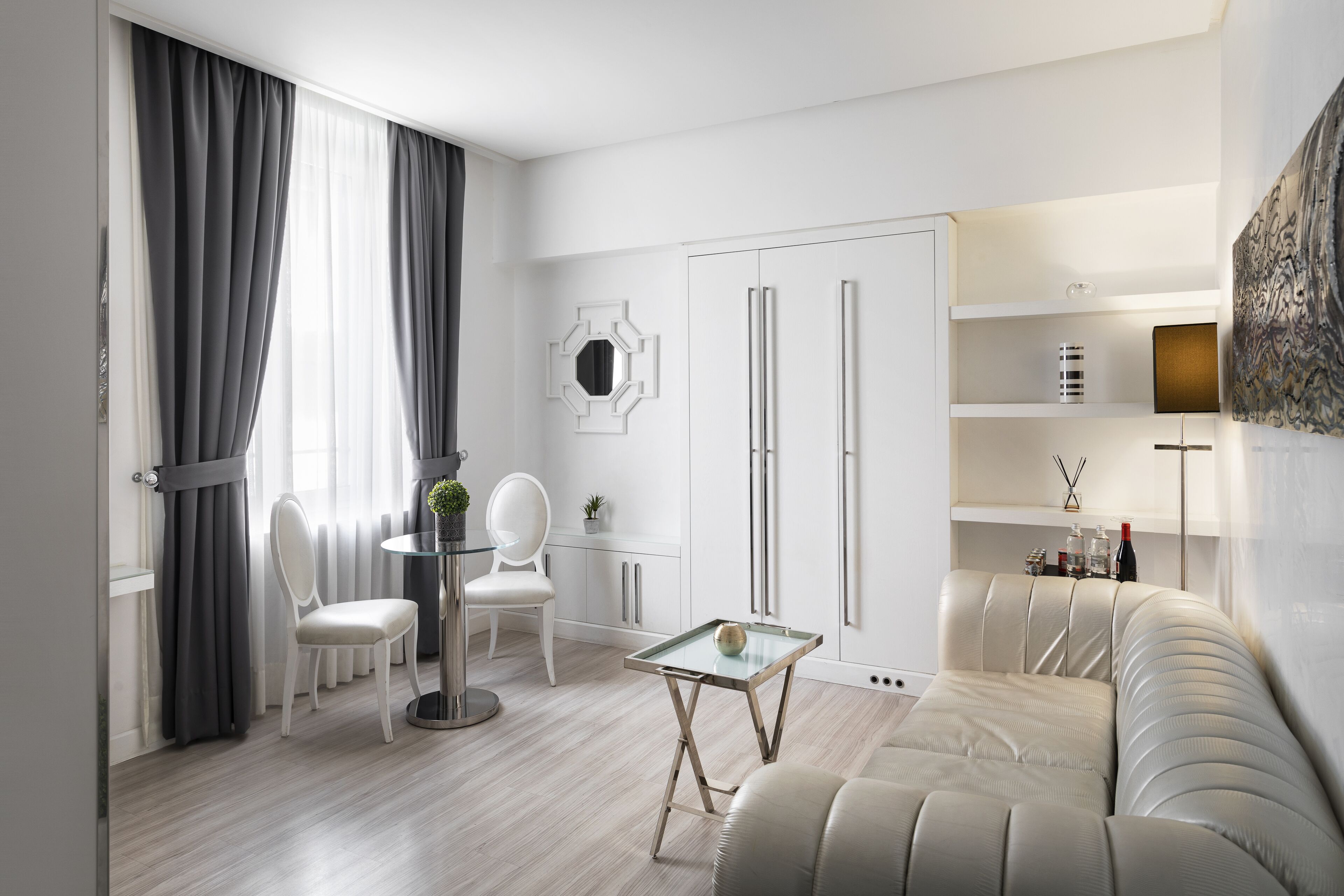 Una sala moderna con un sofá, una mesa de centro de vidrio, una mesa de comedor con sillas y un armario blanco.