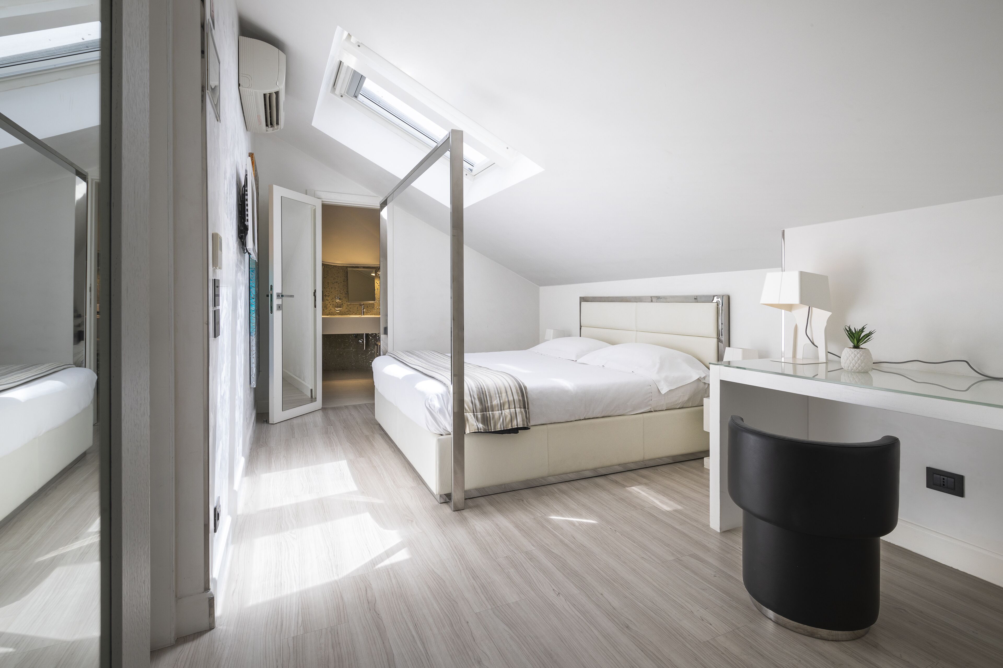 Une chambre moderne avec un lit, un bureau et une fenêtre de toit.