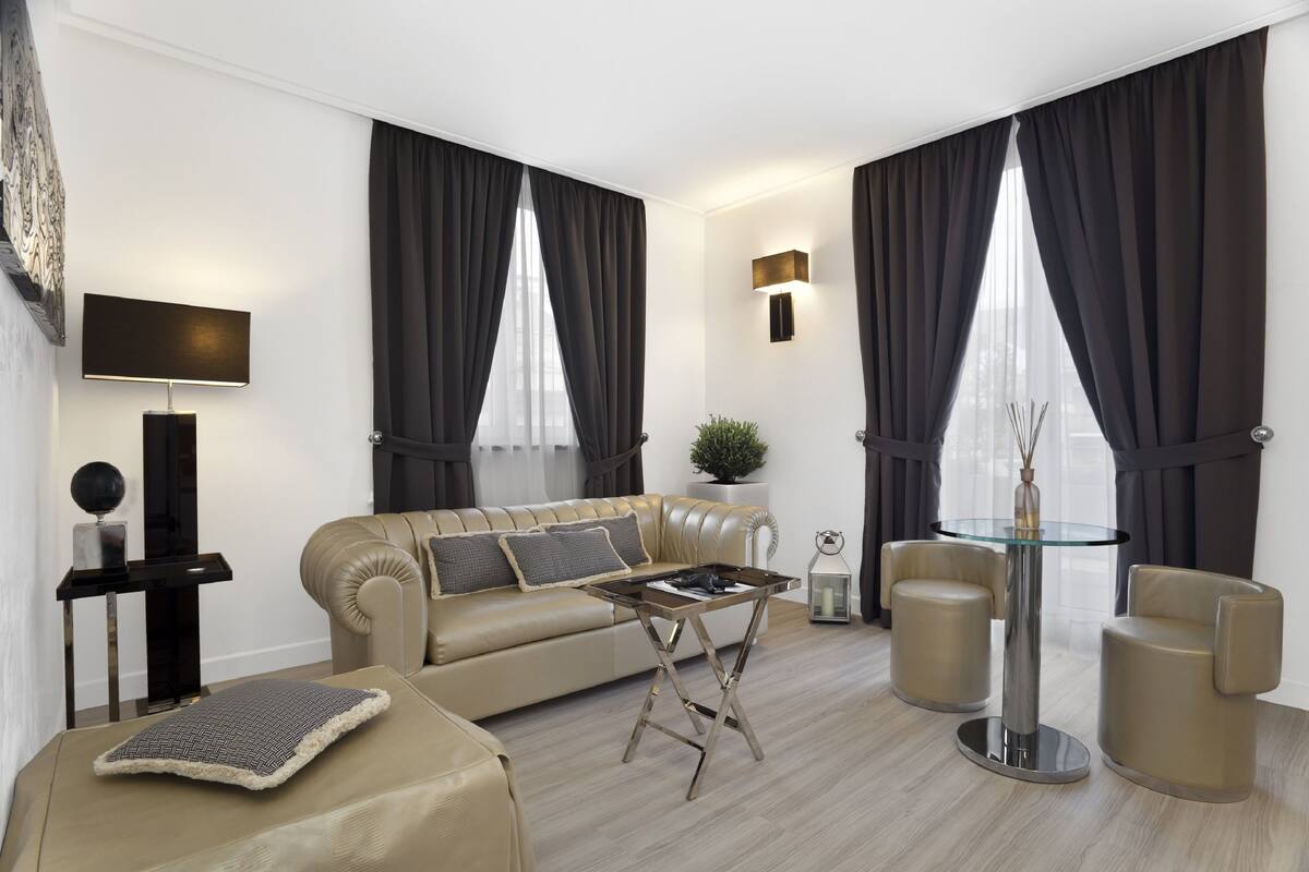 A modern living room with a beige sofa, a glass coffee table, and two armchairs.