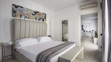 A modern bedroom with a large bed, bedside tables, a bench, and a painting on the wall.
