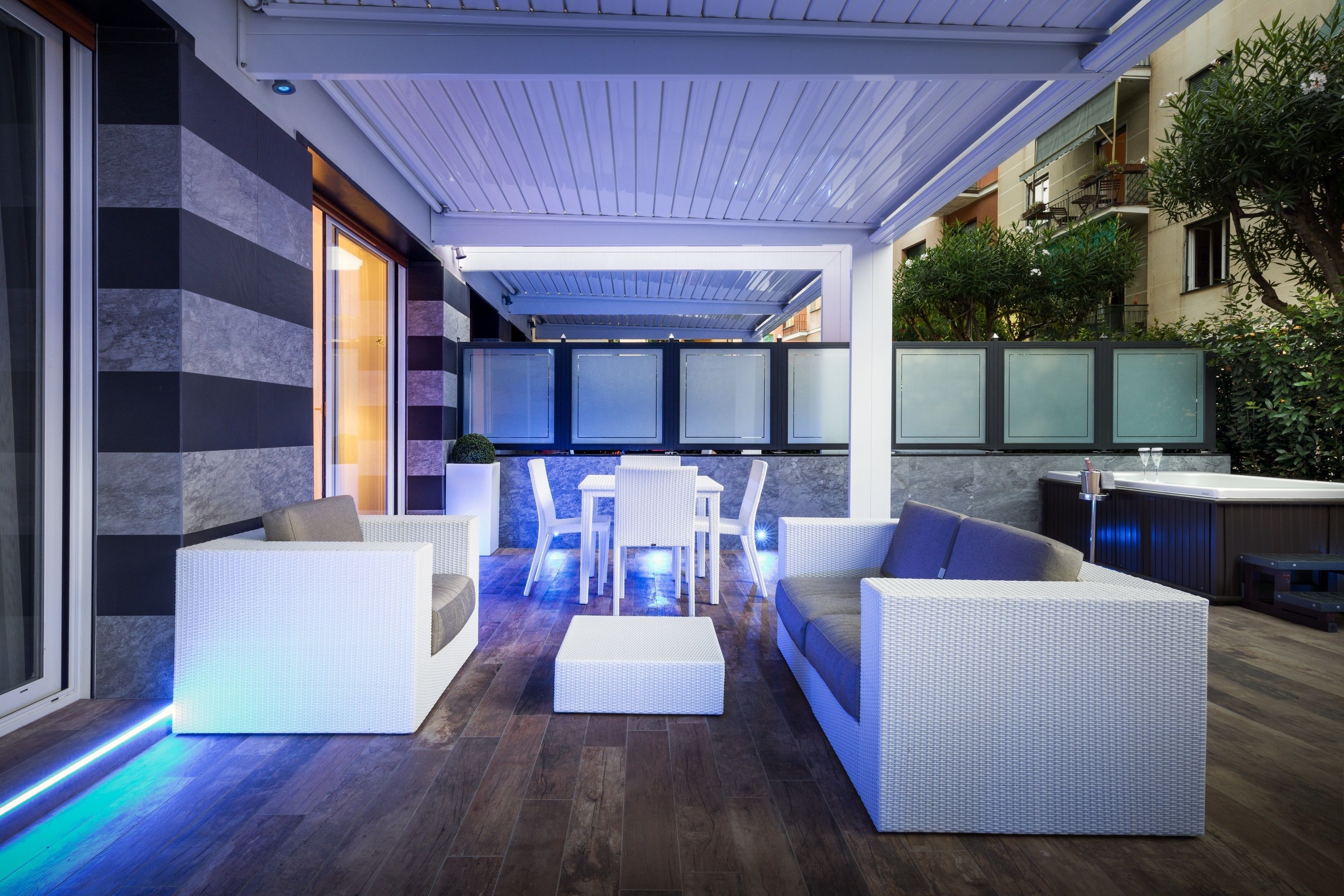 Une terrasse extérieure avec des meubles en osier blanc, une table à manger et un jacuzzi.