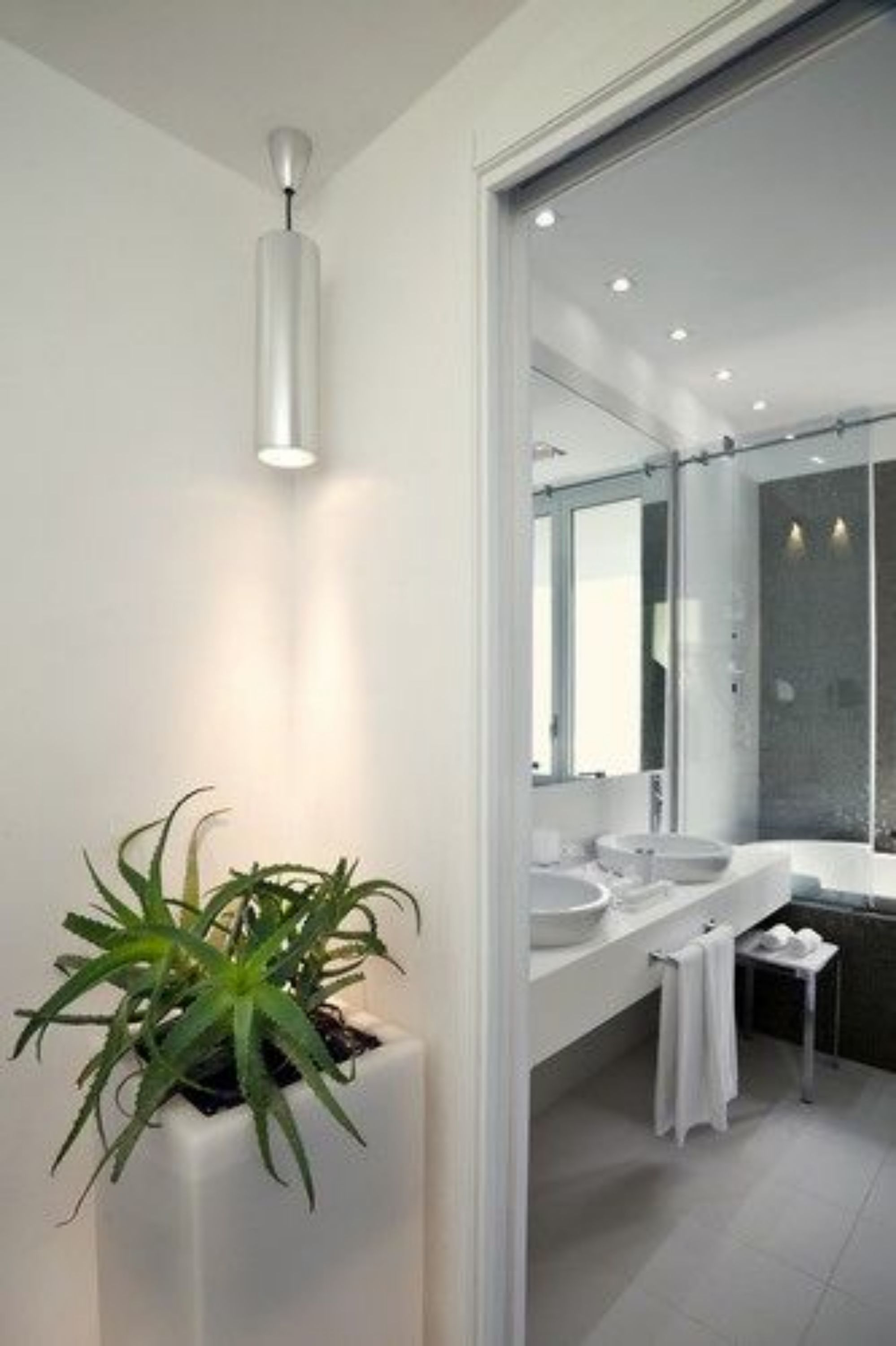 Ein modernes Badezimmer mit einem großen Spiegel, zwei Waschbecken und einer Topfpflanze.