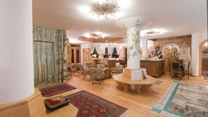 Ein geräumiges Wohnzimmer mit Holzboden, einem runden Holztisch und mehreren gepolsterten Sesseln.