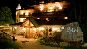 Ein Hotel im traditionellen europäischen Baustil, mit einem markanten Eingang, einem Balkon mit Geländer und einem Schild mit der Aufschrift 'Hotel Petel'.