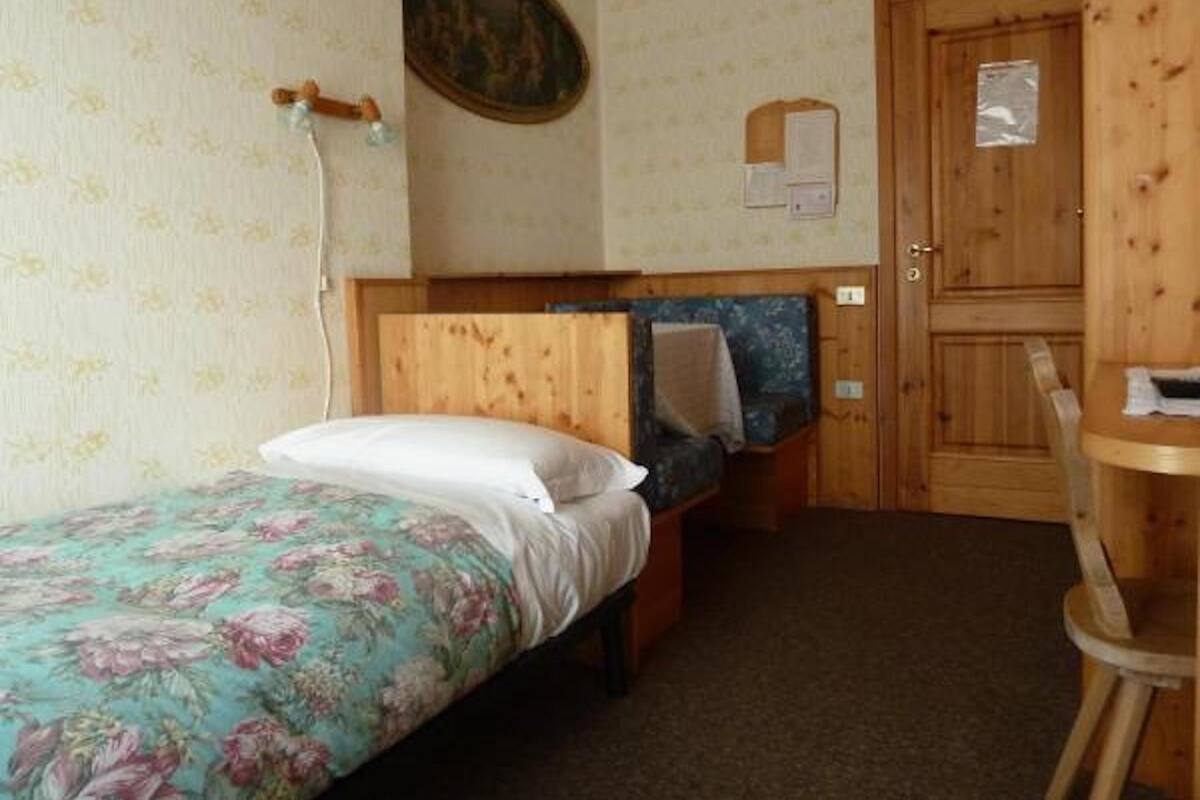 A small bedroom with a single bed, a wooden door, and a small table.
