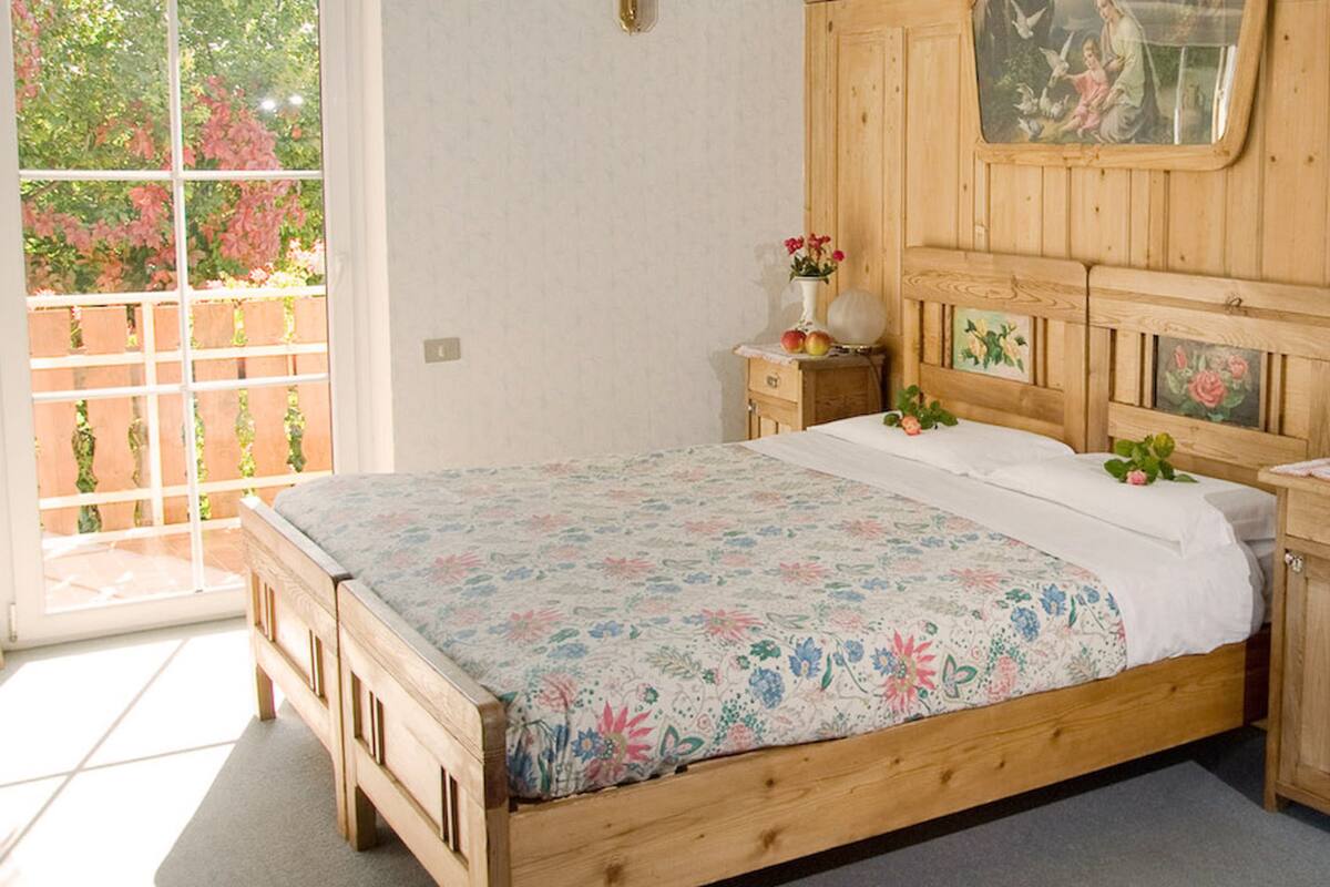 A wooden bedroom with a bed, bedside tables, a nightstand, and a wooden wardrobe.