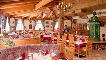 A traditional inn with wooden beams, chandeliers, and a cozy dining area with tables set for meals.