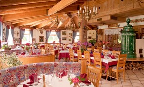 A traditional inn with wooden beams, chandeliers, and a cozy dining area with tables set for meals.