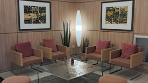 A modern lounge area with a central coffee table, four armchairs, and two round ottomans.