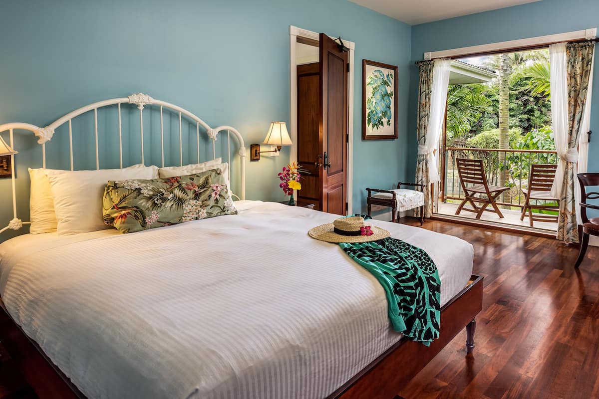 Une chambre à coucher comprenant un lit, une table de chevet, une lampe, une fenêtre avec des rideaux et un balcon avec des chaises.
