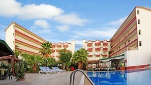 Un hôtel à plusieurs étages, doté d’une piscine et d’un espace extérieur aménagé pour s’asseoir.