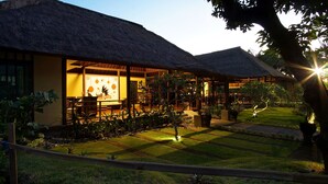 A resort with thatched-roof buildings, a well-maintained garden, and a 'Happy New Year' sign.