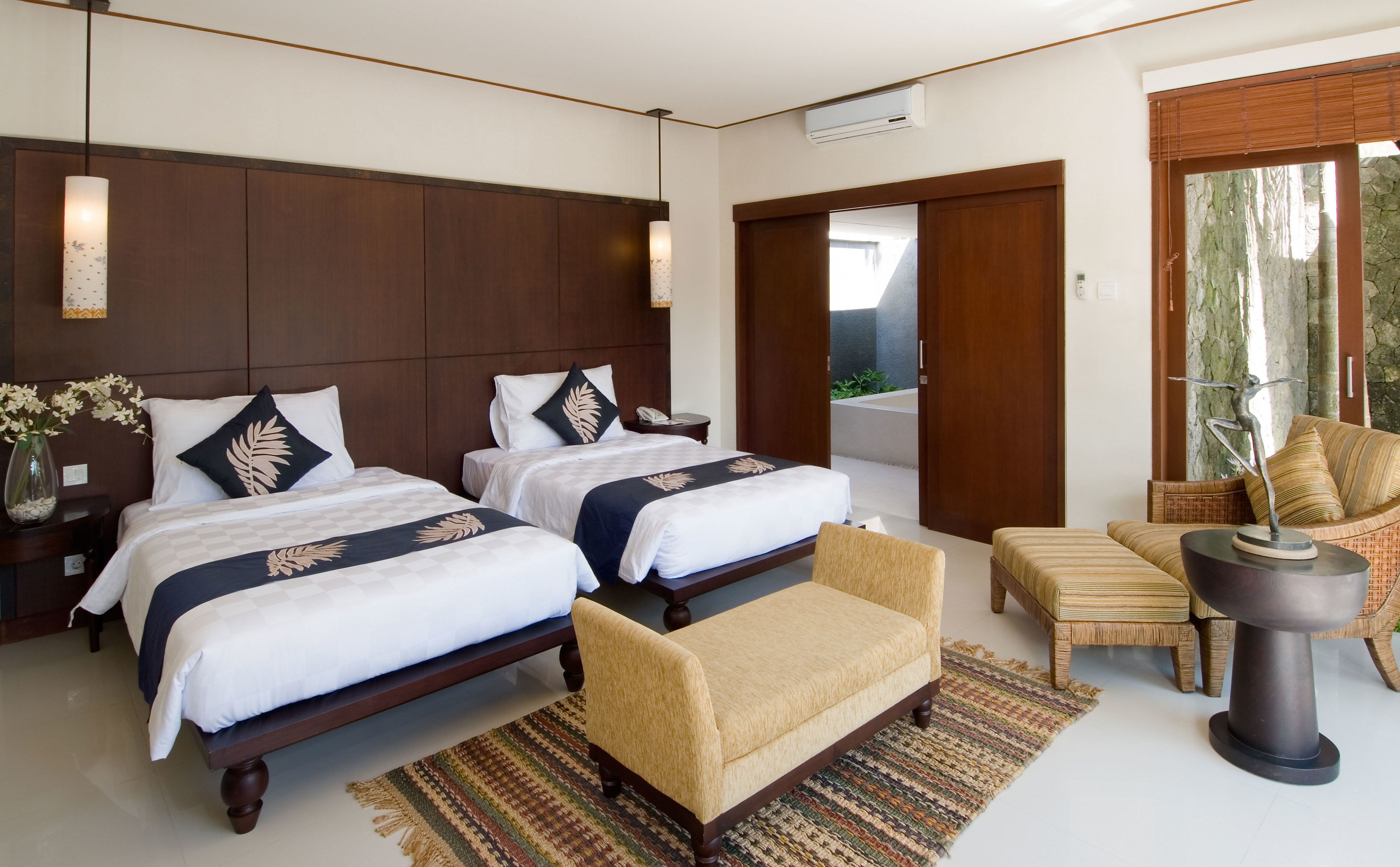 Habitación de hotel con dos camas, un sofá, una silla, una mesita y una escultura decorativa.