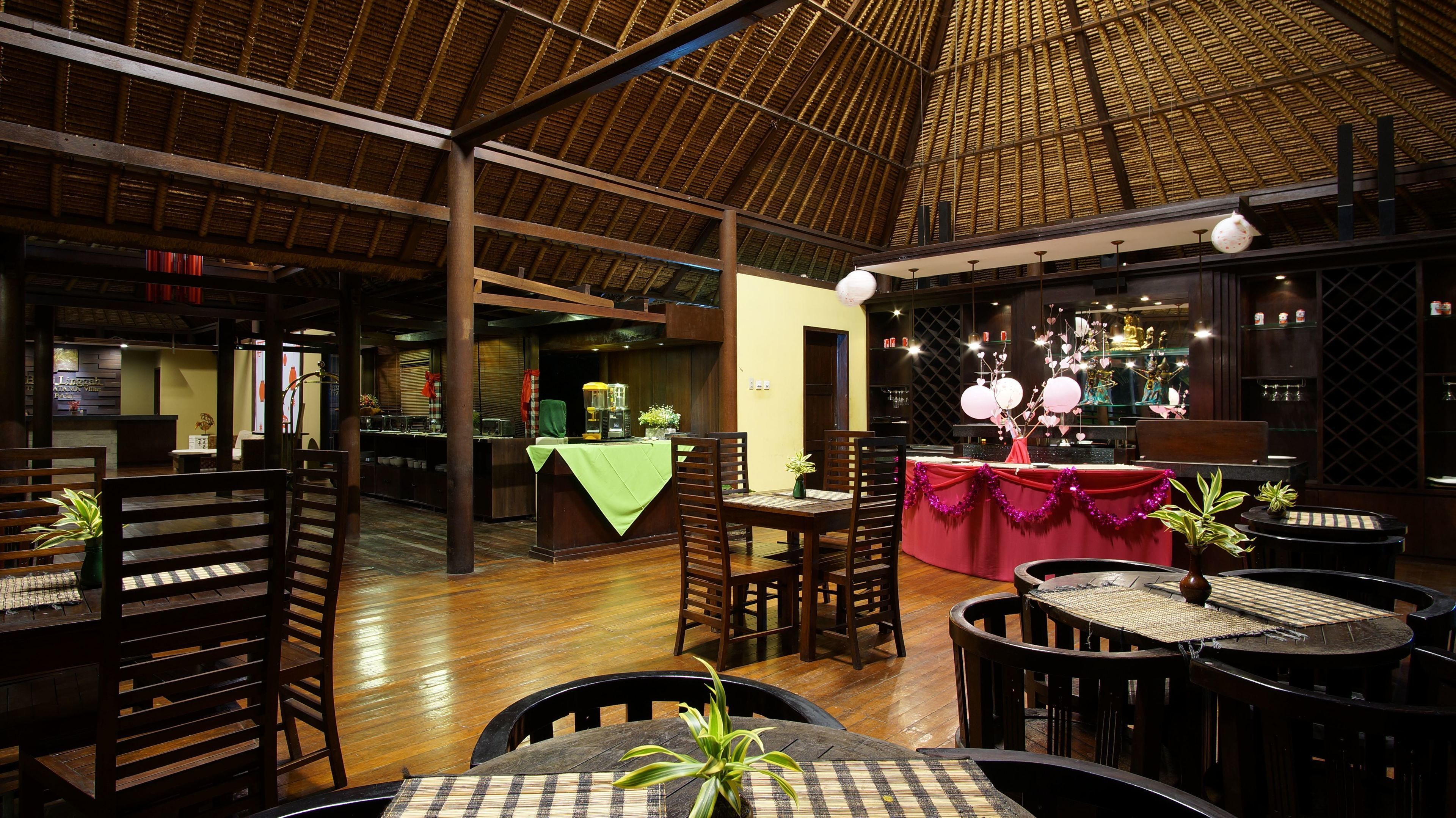 A restaurant with wooden furniture, a thatched roof, and a bar area.