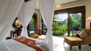 A bedroom with a bed, a chair, and a view of the garden.