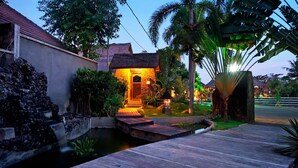 A house with a stone facade, a small pond, and a wooden deck.