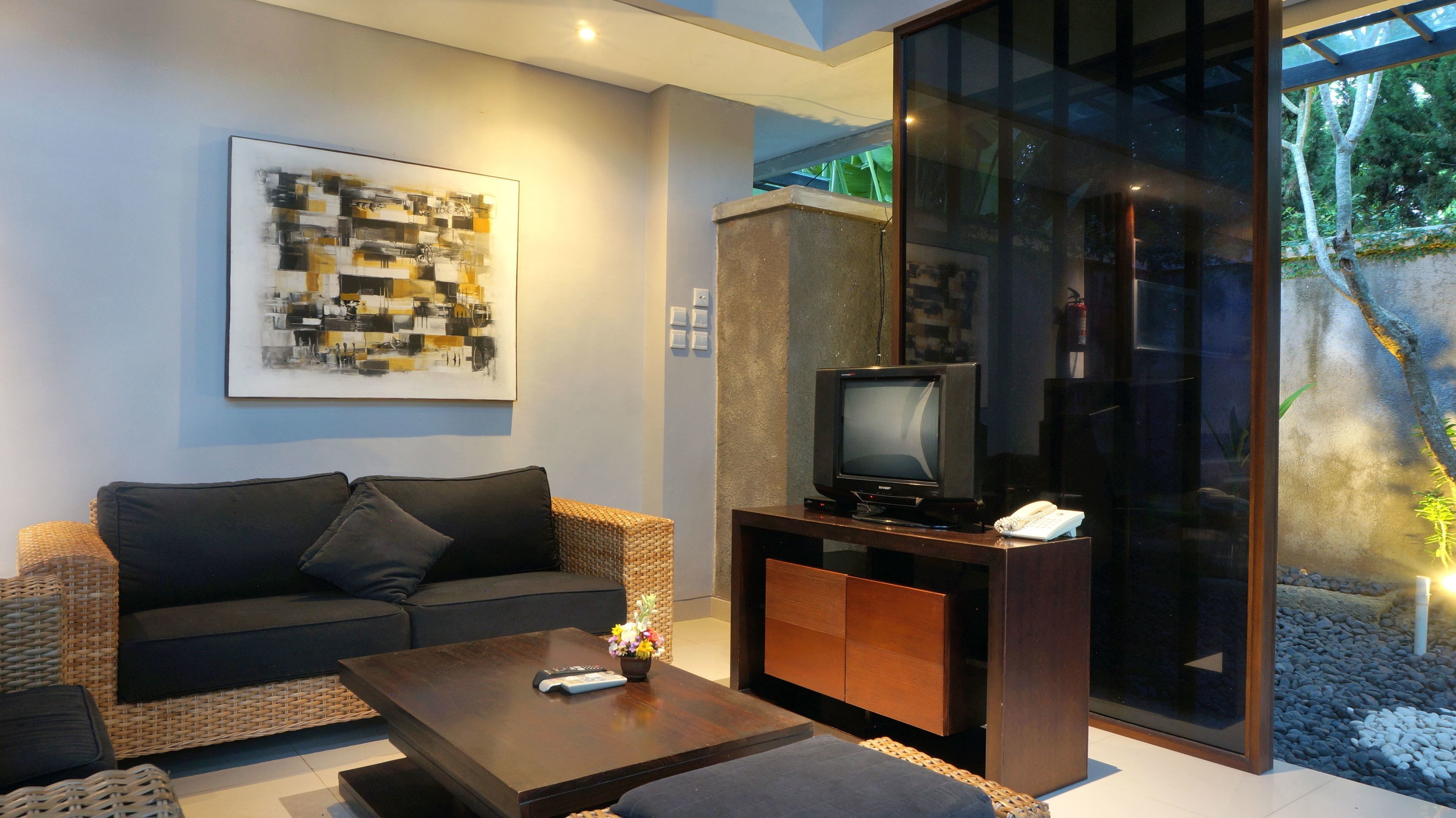 A modern living room with a sofa, coffee table, and a television on a wooden stand.