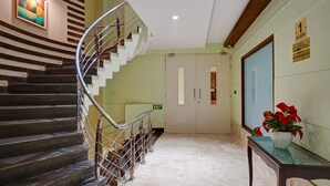 Vestíbulo de hotel con una escalera de caracol, una recepción y una puerta con la indicación "EXIT".