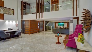 Un vestíbulo amplio con mostrador de recepción, zona de estar y una escalera que conduce a un nivel superior.