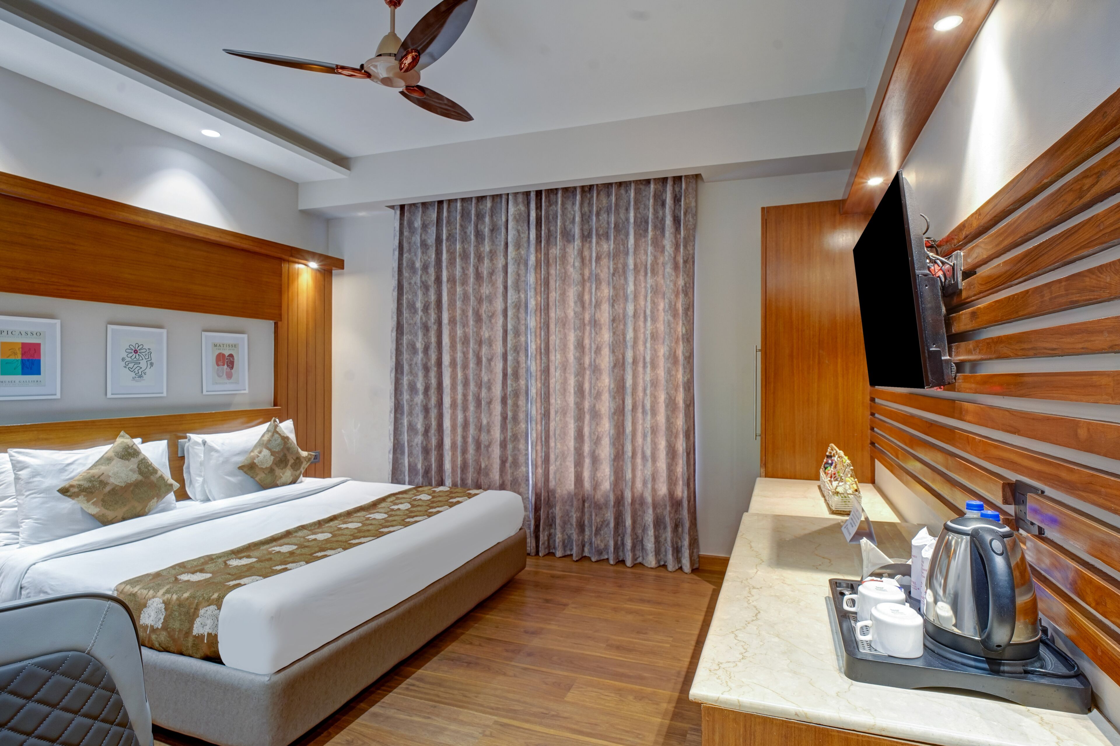 A hotel room with a bed, a bedside table with a coffee maker, and a ceiling fan.