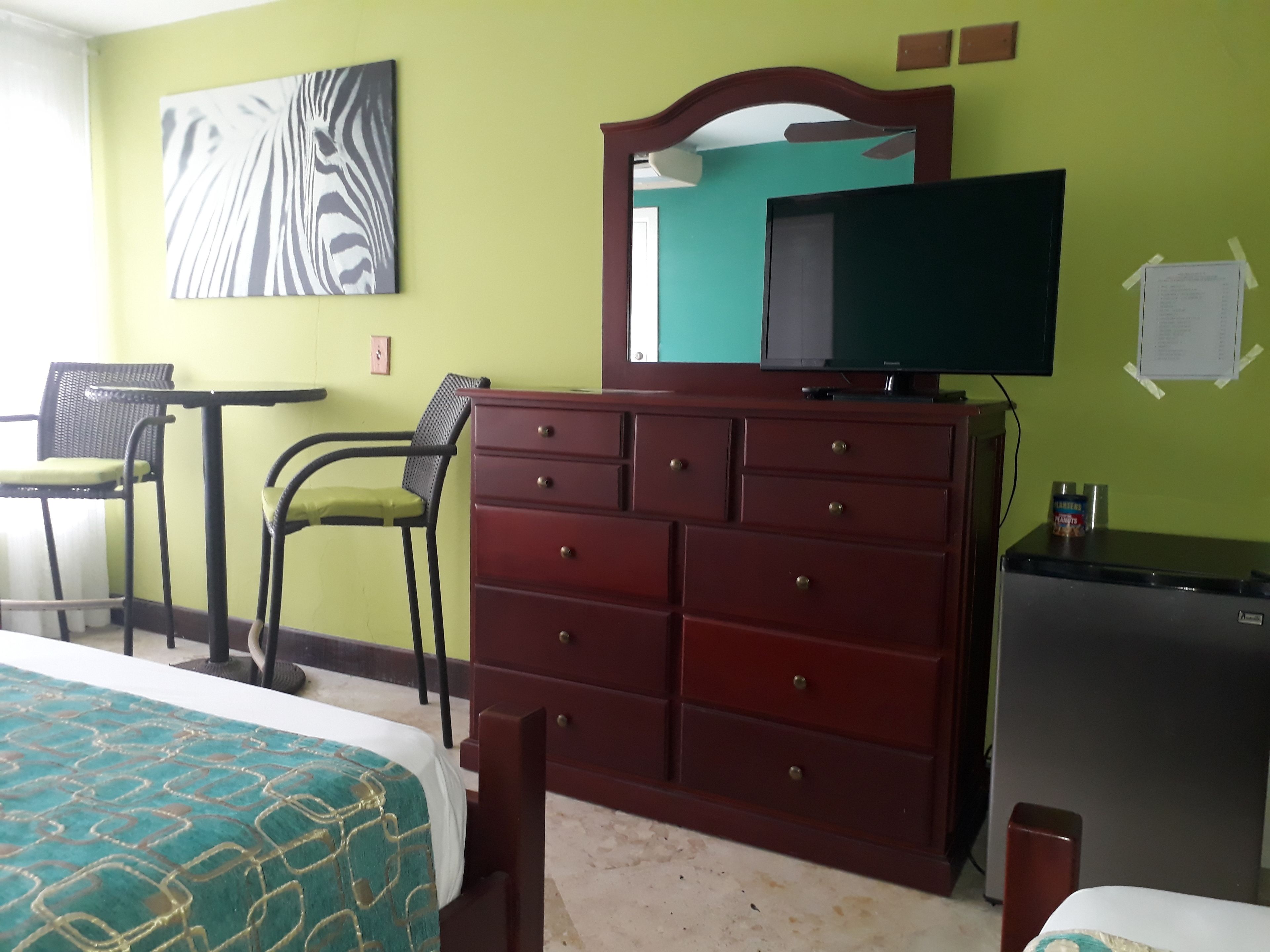 A hotel room with a bed, a dresser, a television, and a chair.