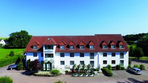 Un hôtel avec un toit recouvert de tuiles rouges, de nombreuses fenêtres et une enseigne indiquant qu’il s’agit d’un hôtel.