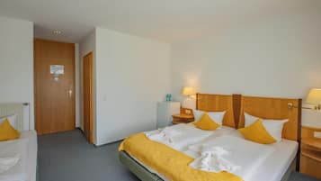 Ein Hotelzimmer mit Doppelbett, zwei Nachttischen, einem Heizkörper und einer Tür mit einem Hinweis.