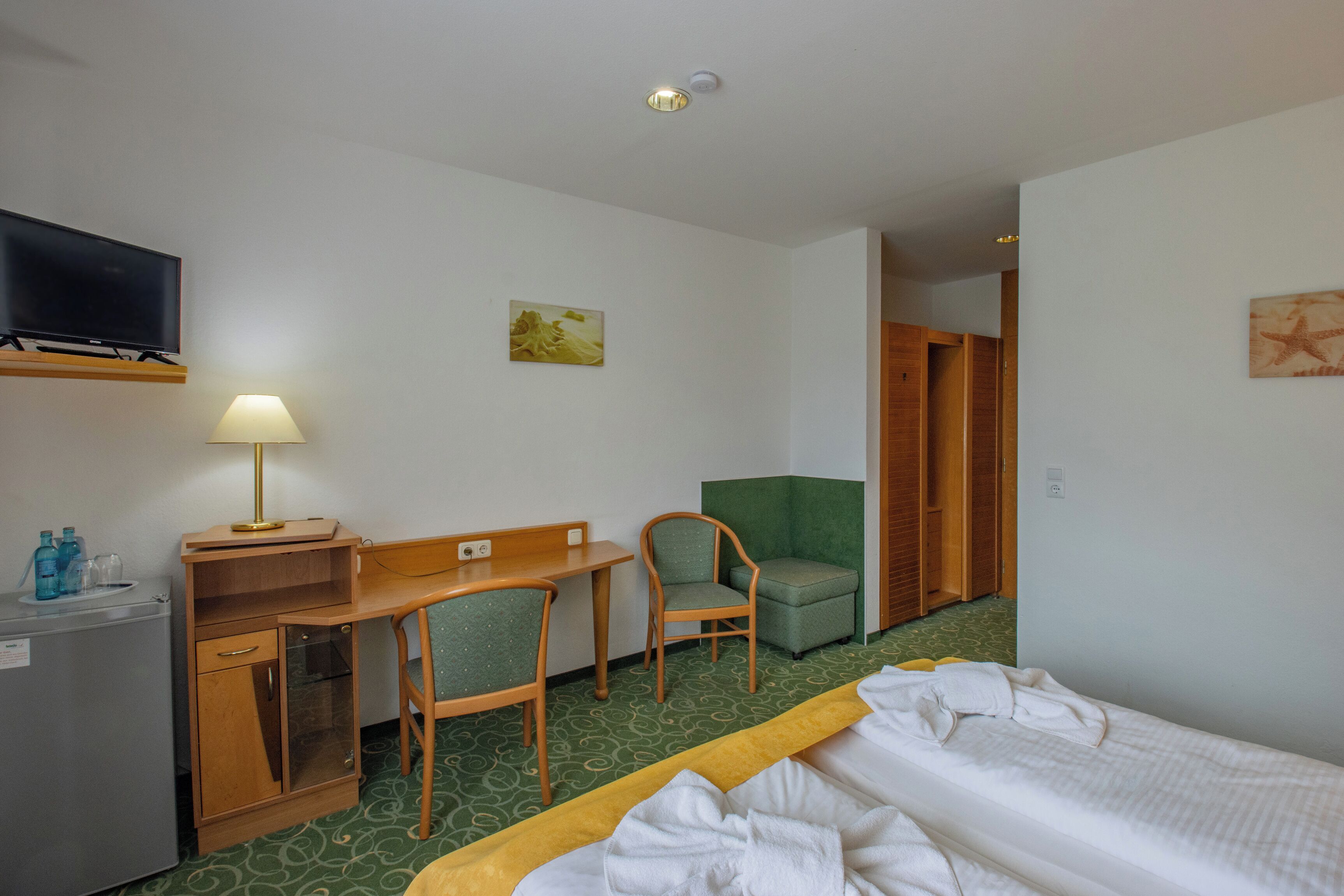 Een hotelkamer met een bed, een bureau, een stoel, een televisie en een kledingkast.