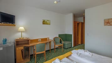 Een hotelkamer met een bed, een bureau, een stoel, een televisie en een kledingkast.