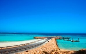 A coastal road with a beach and a pier. - RAC Ningaloo Reef Resort (Coral Bay)