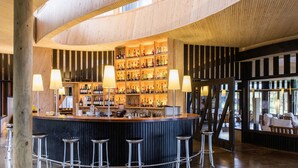 A bar area with a wooden ceiling, bar stools, and a well-stocked liquor shelf. - explora Rapa Nui (Hanga Roa)