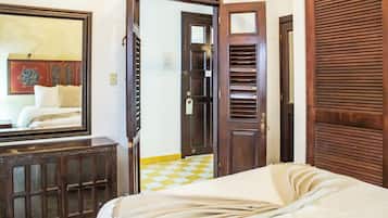 Una habitación de hotel con una cama, un armario de madera, una puerta y un suelo a cuadros.