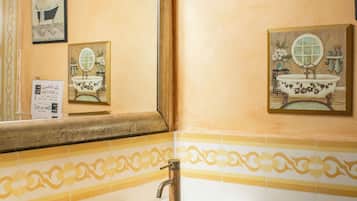 Een badkamer met een houten wastafelmeubel, een grote spiegel en een toiletrolhouder aan de muur.