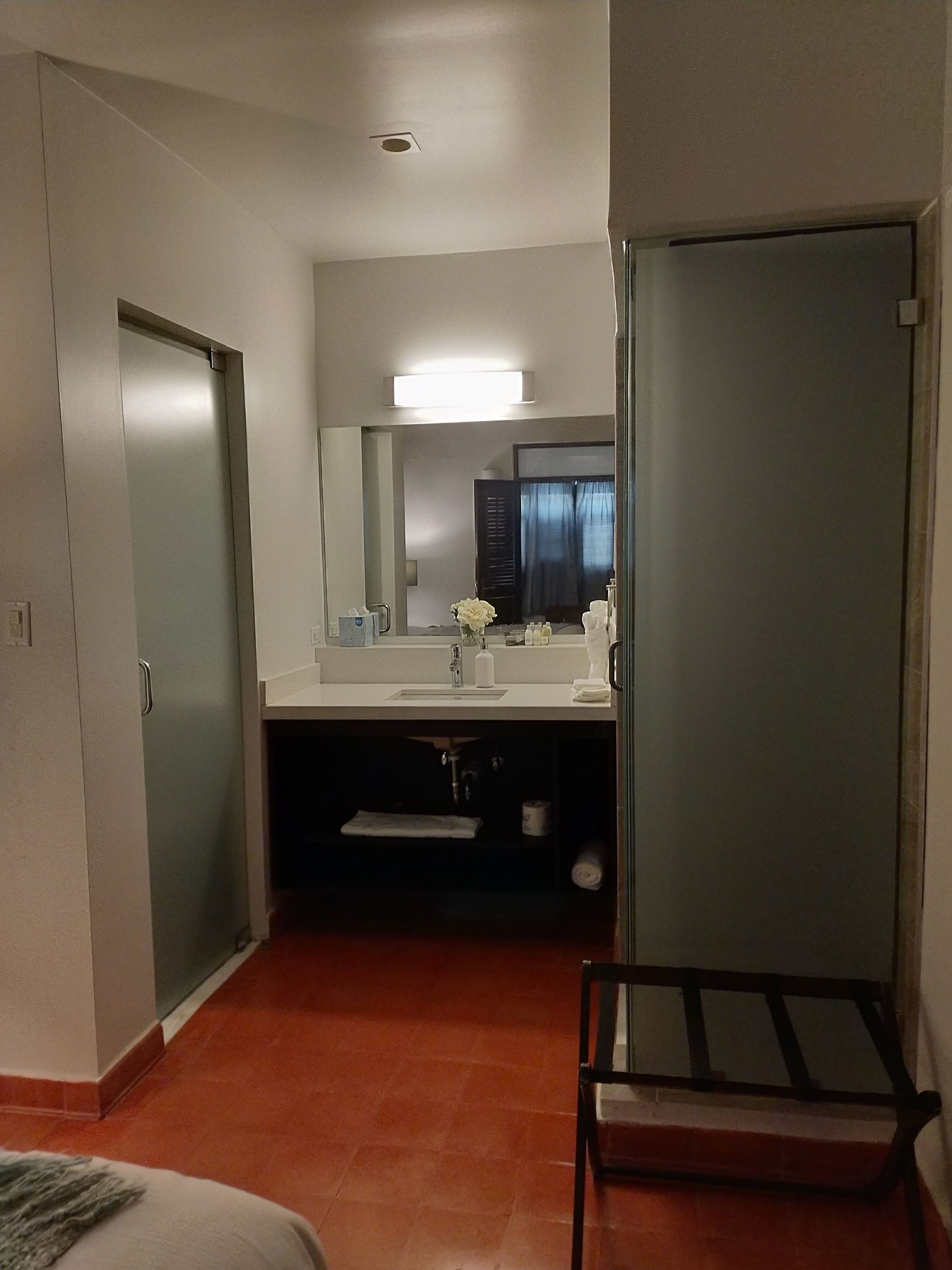 Un baño de hotel con lavamanos, espejo y perchero para toallas.